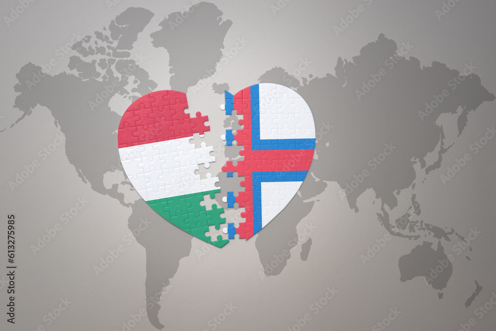 puzzle heart with the national flag of faroe islands and hungary on a world map background.Concept.