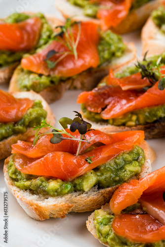 Fresh bruschetta with salmon, avocado and microgreens, closeup.