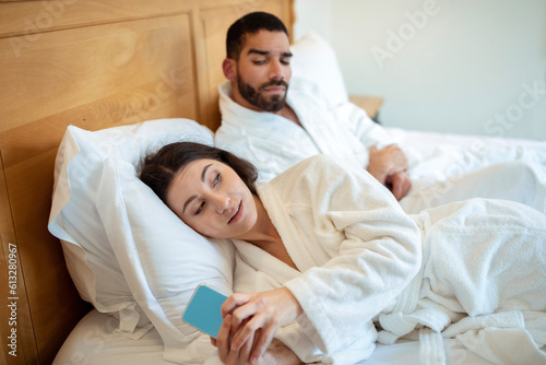 Arabic Husband Reading Wife's Messages On Cellphone Lying In Bedroom