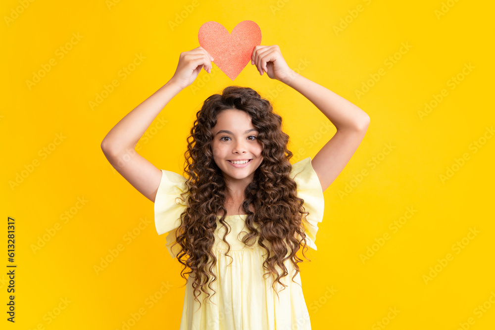Naklejka premium Happy teenager portrait. Lovely child teen girl with shape heart love holiday and valentine symbol. Valentine or birthday day. Gift heart present. Smiling girl.