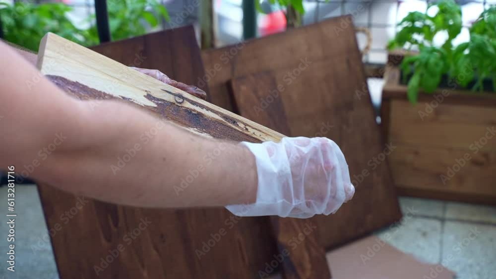 Carpenter in gloves restoring wooden board surface, worker polished wood surface and colouring