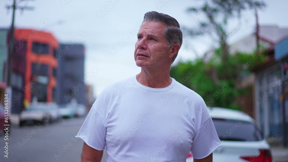 Pensive senior man walking in street in daylight. A middle-age caucasian male strolling in urban environment with thoughtful expression, contemplative emotion