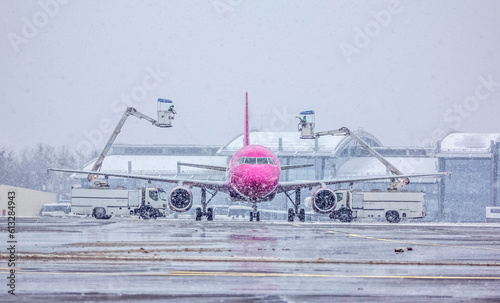 
Deicing, airport services de-icing the structure of a pink and white passenger plane, the plane is cleared of people in winter. Flight safety, aviation safety