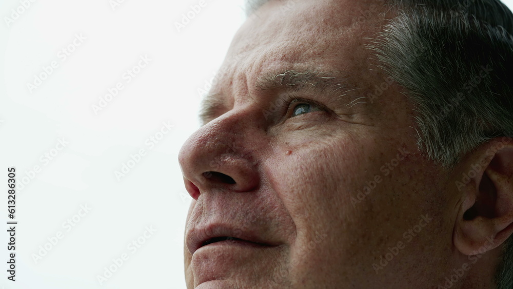 Obraz premium Contemplative older man close-up face looking up at sky with thoughtful expression, person closing eyes in meditation