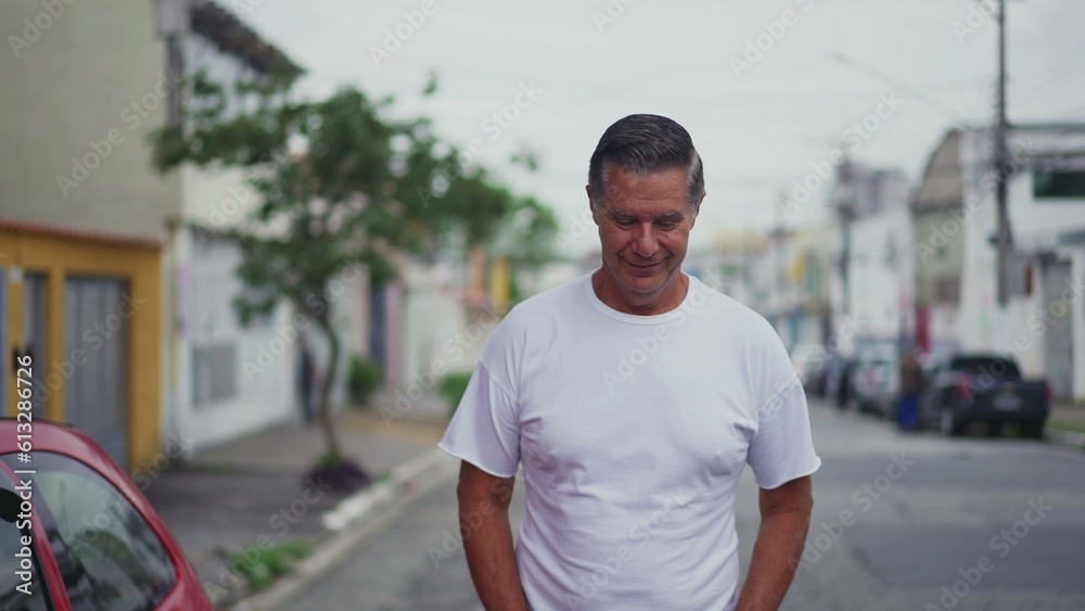 Contemplative happy middle-age man walking in city street with happy expression, an older person walking forward toward camera Contemplative happy middle-age man walking in city street with happy expression, an older person walking forward toward camera