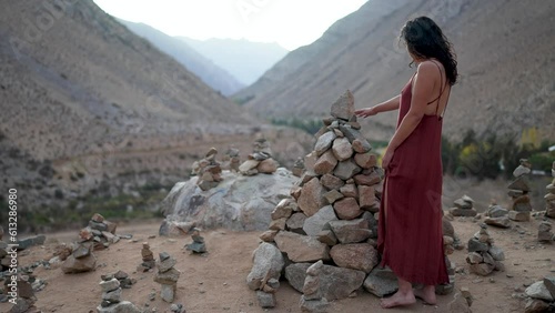 latin american woman in cochiguaz valley looking at stone pile photo