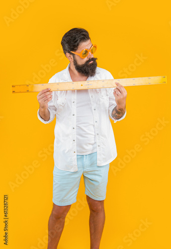 image of man hold measuring ruler. man hold measuring ruler isolated on yellow.