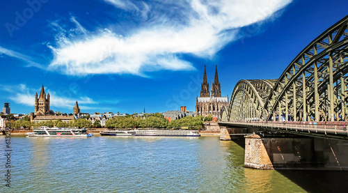 Cologne (Köln), Germany - June 6. 2023: Beautiful rhine river city skyline, two churches, old Hohenzollern steel bridge photo