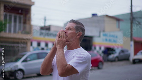 Religious Senior man standing on street in Prayer. Devoted middle-age male caucasian person Praying to God looking at sky smiling exuding HOPE and FAITH