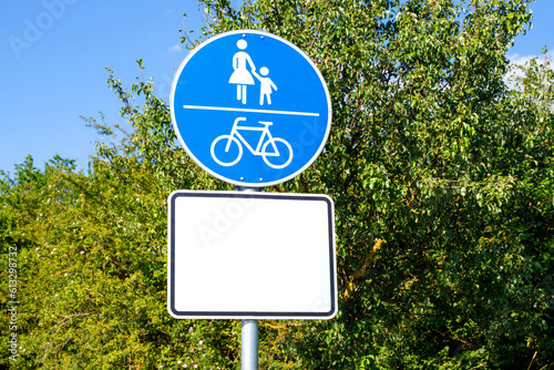 Road sign cycle and pedestrian pathway against of a green tree