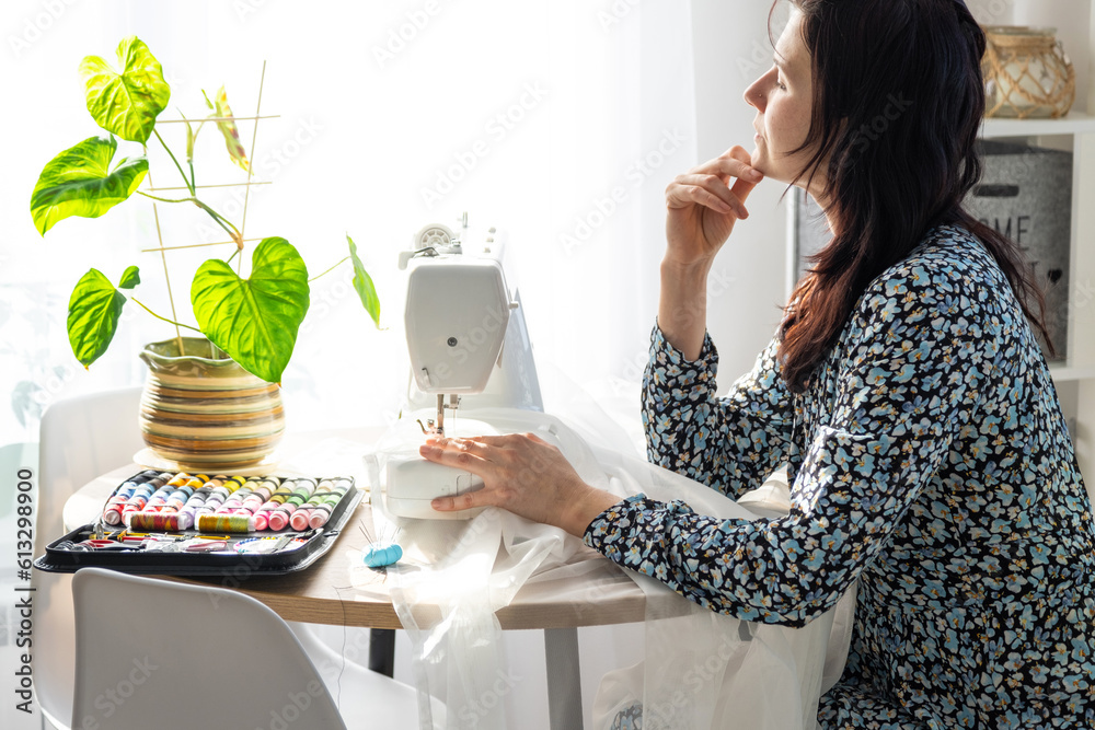 Woman thinking, dreaming and sews tulle on an electric sewing machine