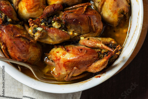 Obraz na płótnie Baked quail stuffed with mushrooms, eggs and bread in a ceramic form on a wooden table. w salonie