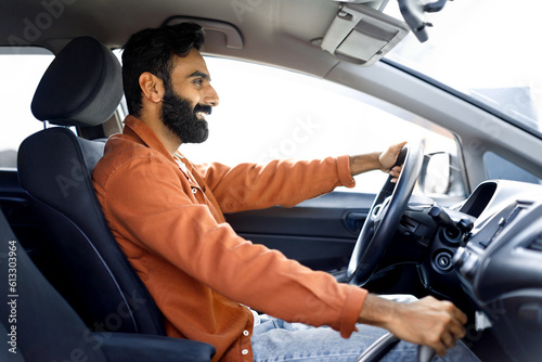 Side View Of Cheerful Middle Eastern Man Driving Comfortable Auto