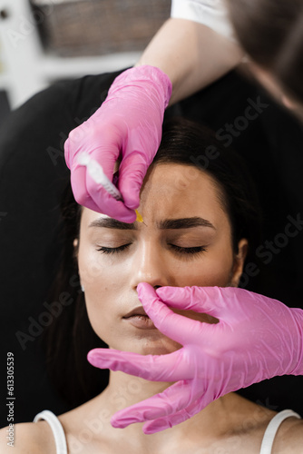 Beautician is injecting botulinum toxin to correct mimic wrinkles and hyperhidrosis for young girl. Botulinum toxin to relax and neutralize overactive muscles that cause wrinkles.