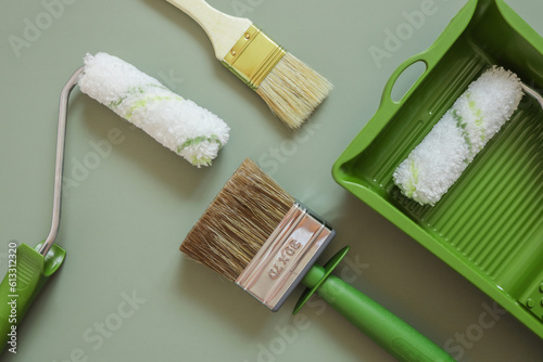 Fototapeta Naklejka Na Ścianę i Meble -  Wall paint roller and brush on green background, top view
