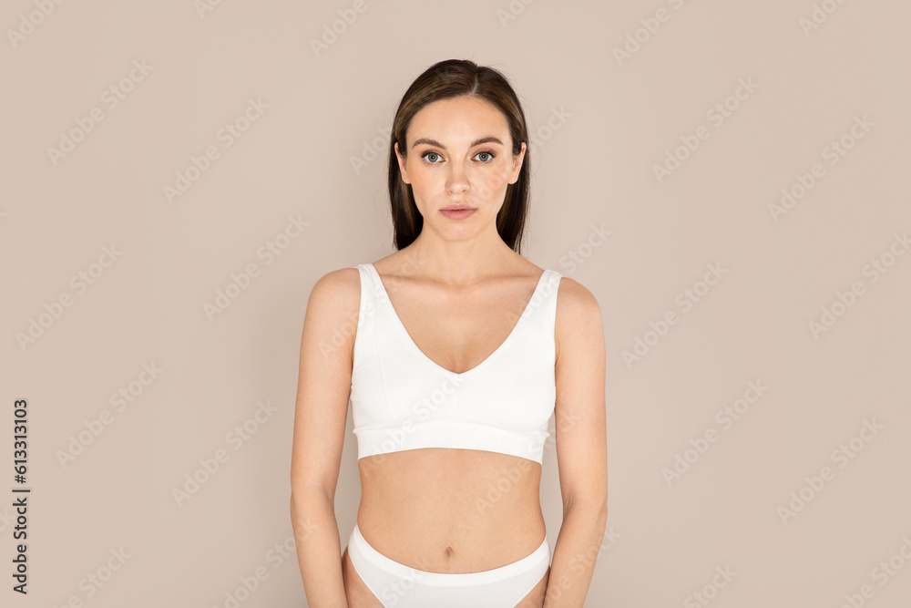 Attractive young woman posing in underwear on beige background Attractive young woman posing in underwear on beige background
