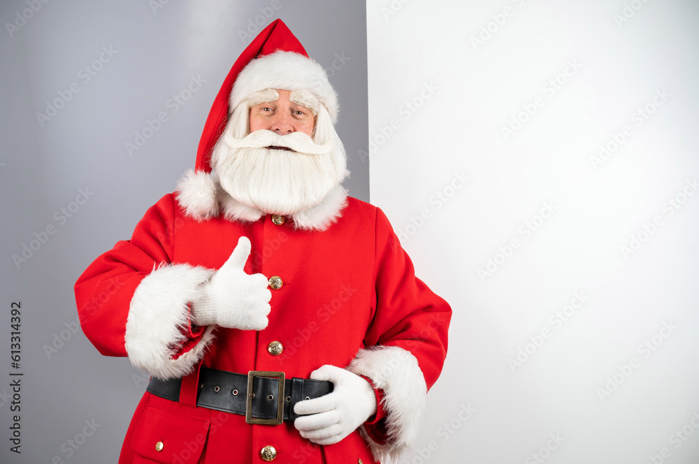 Santa claus peeks out from behind an empty Christmas advertisement and shows a thumbs up. Santa claus peeks out from behind an empty Christmas advertisement and shows a thumbs up.