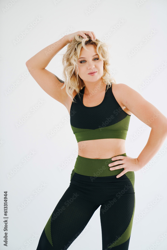 an attractive blonde in a black and green tracksuit poses on a white background. an attractive blonde in a black and green tracksuit poses on a white background.