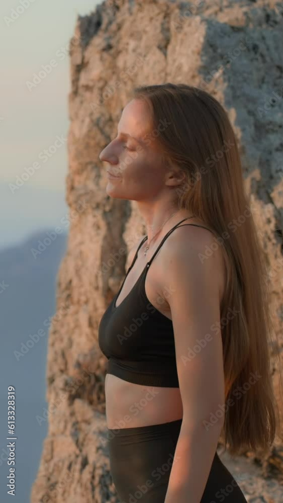 Young woman, standing on a hill, sunrise, performs neck warm up. Young woman, standing on a hill, sunrise, performs neck warm up.