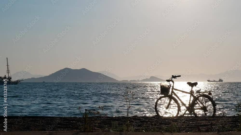Silhouette of a bicycle against the background of a boat floating in the sea. Silhouette of a bicycle against the background of a boat floating in the sea.