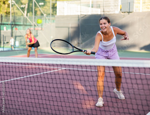 Young sporty woman tennis player dressed white t-shirt and shorts hitting ball with racket on court
