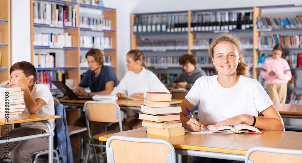 Portrait of a teenage girl in the school library. Preparing for the exam