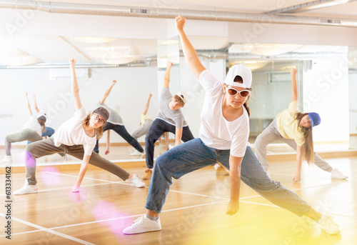 Focused teenage hip hop dancers doing dance workout during group class