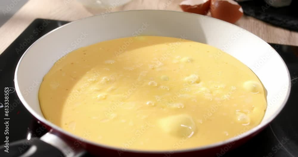 Eggs with milk are fried into a frying pan. Making an omelet. Cooking traditional breakfast from eggs. Close up. Smooth camera movement. Sunny day. High quality 4k footage