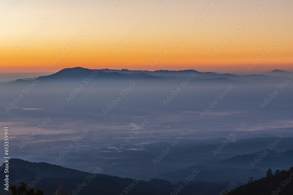 Heaven at early morning with mountains in a fog. Sunset, sunrise backdrop.Predawn clear sky with orange horizon. Smooth orange blue gradient of dawn sky.