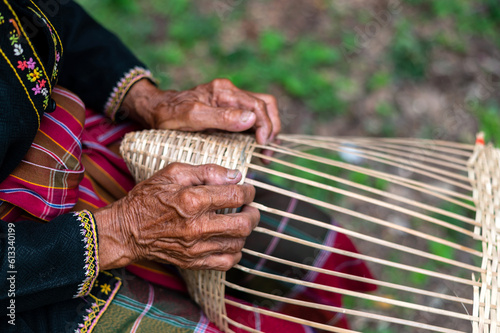 Close up Old man Hand weaving wicker basket or bamboo basketry  indoors.Weaving bamboo fish trap in Thailand.closeup view photo