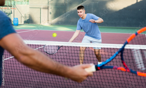 Concentrated young man tennis player hitting ball with a racket