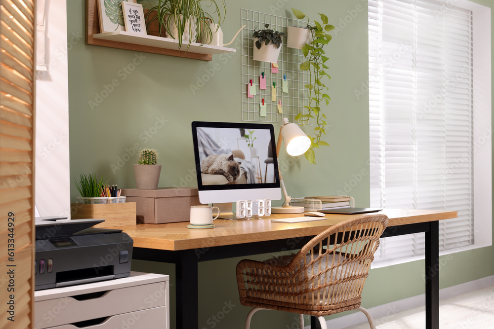 Stylish workplace with computer, laptop and lamp near olive wall at home Stylish workplace with computer, laptop and lamp near olive wall at home
