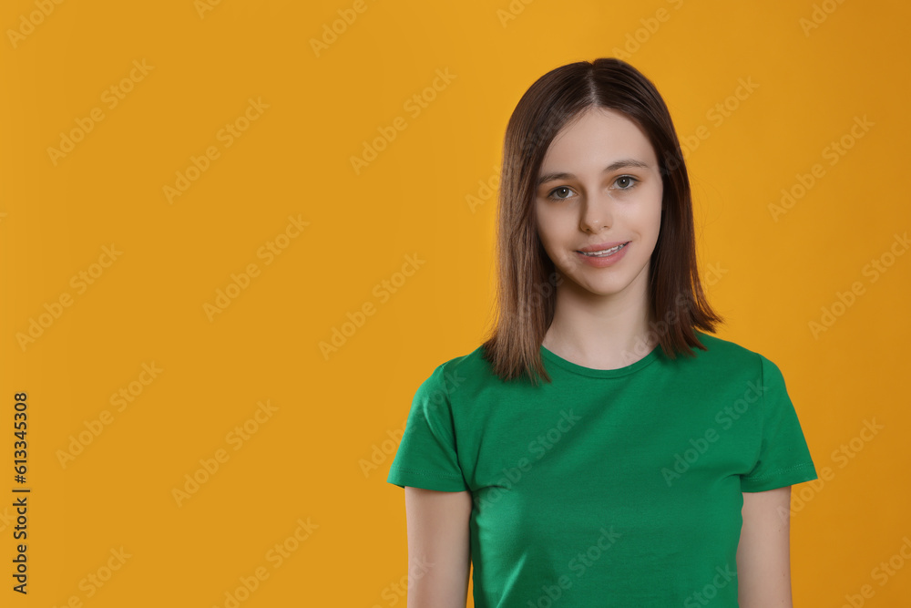 Portrait of smiling teenage girl on orange background. Space for text Portrait of smiling teenage girl on orange background. Space for text