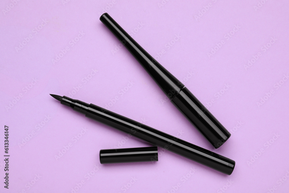 Black eyeliners on lilac background, flat lay. Makeup product Black eyeliners on lilac background, flat lay. Makeup product