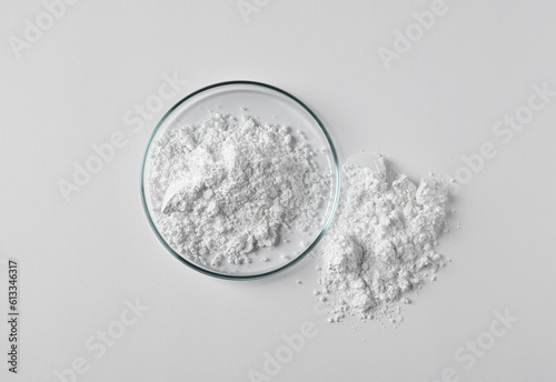 Petri dish and calcium carbonate powder on white background, top view