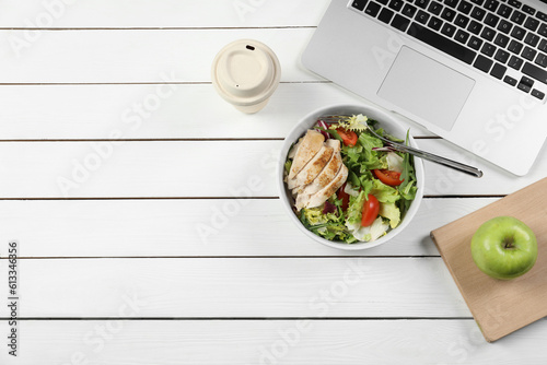 Bowl of tasty food, paper cup of coffee, laptop, apple and book on white wooden table, flat lay with space for text. Business lunch