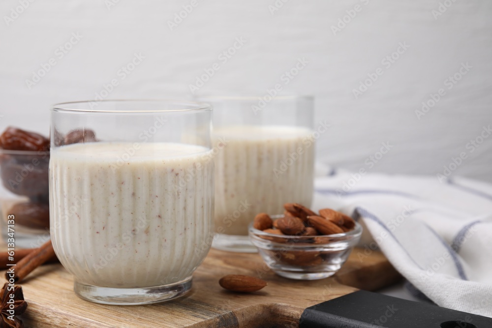 Glasses of delicious date smoothie and nuts on wooden board. Space for text Glasses of delicious date smoothie and nuts on wooden board. Space for text