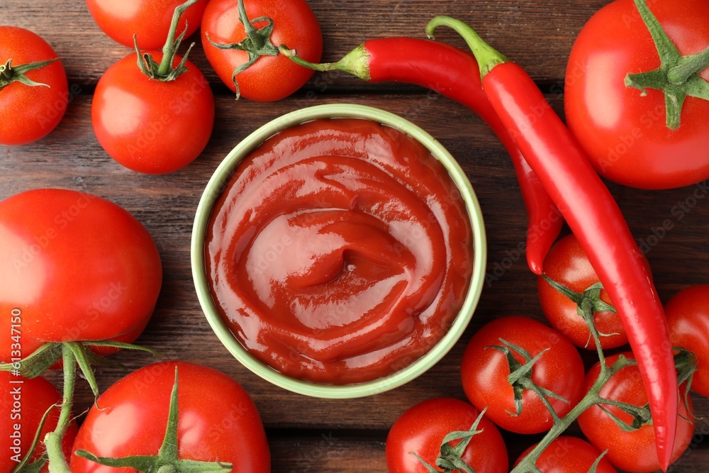 Bowl of tasty ketchup, chili peppers and tomatoes on wooden table, flat lay Bowl of tasty ketchup, chili peppers and tomatoes on wooden table, flat lay