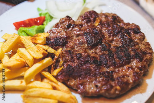 Foto Pljeskavica with french fries on a plate, traditional serbian dish, grilled dish