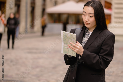 Portrait young happy asian woman tourist in casual clothes on old city street in europe while checking direction on map and navigation on smartphone