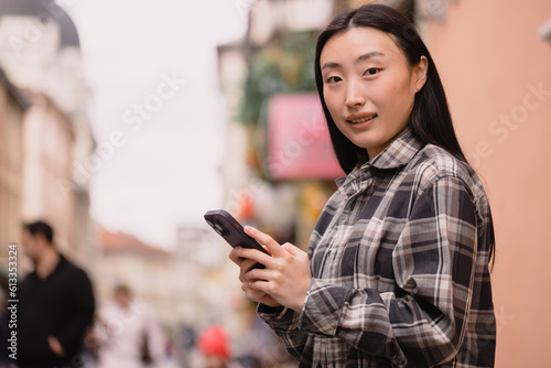 Portrait of a beautiful Korean woman on the old town street. Asian woman in casual clothes talking on the phone, modern technology and lifestyle.