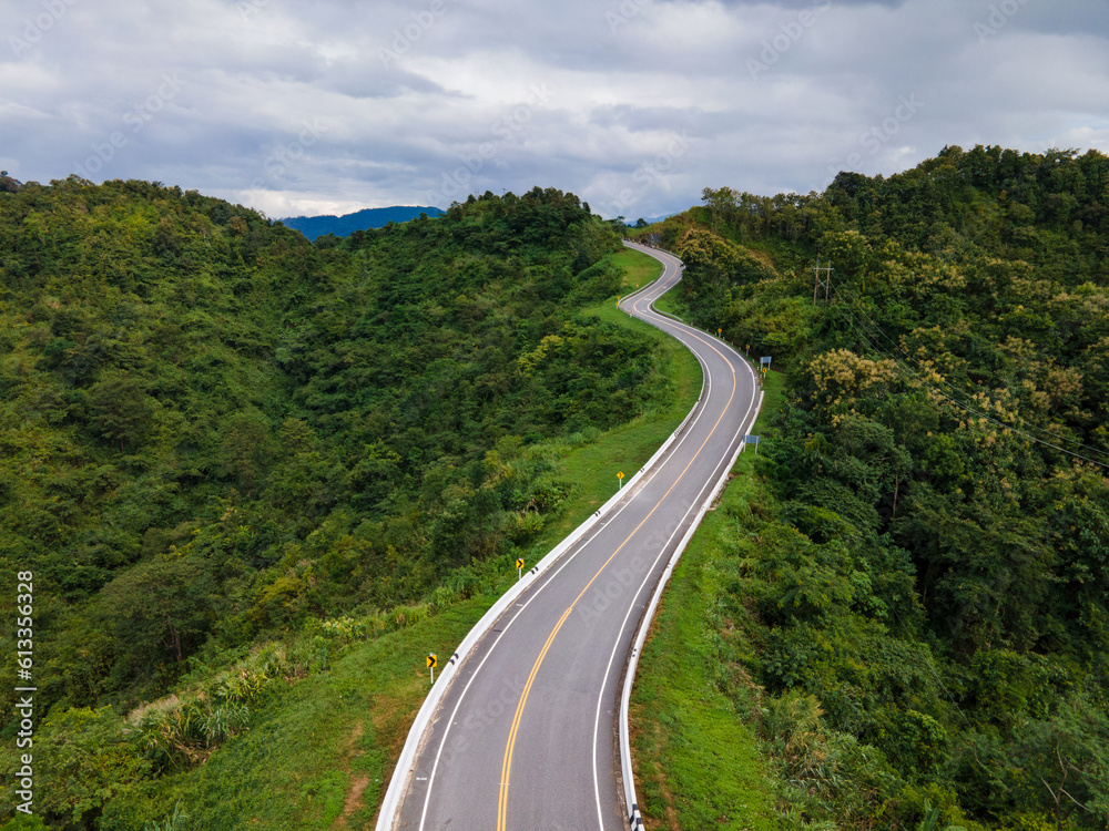 Taken from a drone camera angle at Sky Road, Road No. 3, Unseen, Nan Province, Thailand, meandering along the ridge of the forest. The view is very beautiful. The rainy season is green.