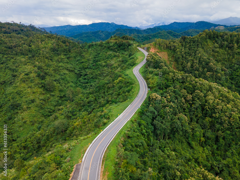 Fototapeta premium Taken from a drone camera angle at Sky Road, Road No. 3, Unseen, Nan Province, Thailand, meandering along the ridge of the forest. The view is very beautiful. The rainy season is green.