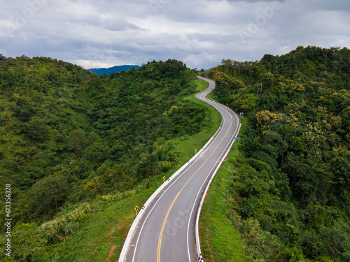 Taken from a drone camera angle at Sky Road, Road No. 3, Unseen, Nan Province, Thailand, meandering along the ridge of the forest. The view is very beautiful. The rainy season is green.