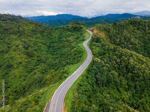 Taken from a drone camera angle at Sky Road, Road No. 3, Unseen, Nan Province, Thailand, meandering along the ridge of the forest. The view is very beautiful. The rainy season is green. © Theerawat