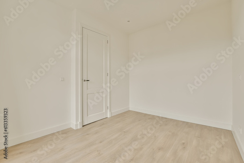an empty room with white walls and wood floors  there is a door leading to the left side of the room