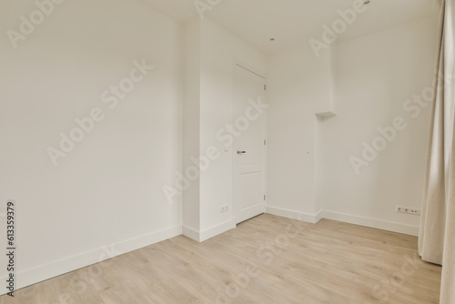 an empty room with white walls and wood flooring on the right side  there is a door in the corner to the left