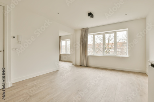 an empty room with white walls and wood flooring  there is a large window in the wall to the right