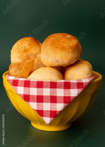 Cheese bread (Brazilian pao de queijo mineiro), front view, focused, on a bowl, green background, vertical photo