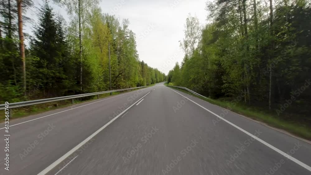 The road winds its way through vast green fields, with majestic trees dotting the landscape. Cars traverse the road, adding movement and life to the serene surroundings. The road winds its way through vast green fields, with majestic trees dotting the landscape. Cars traverse the road, adding movement and life to the serene surroundings.